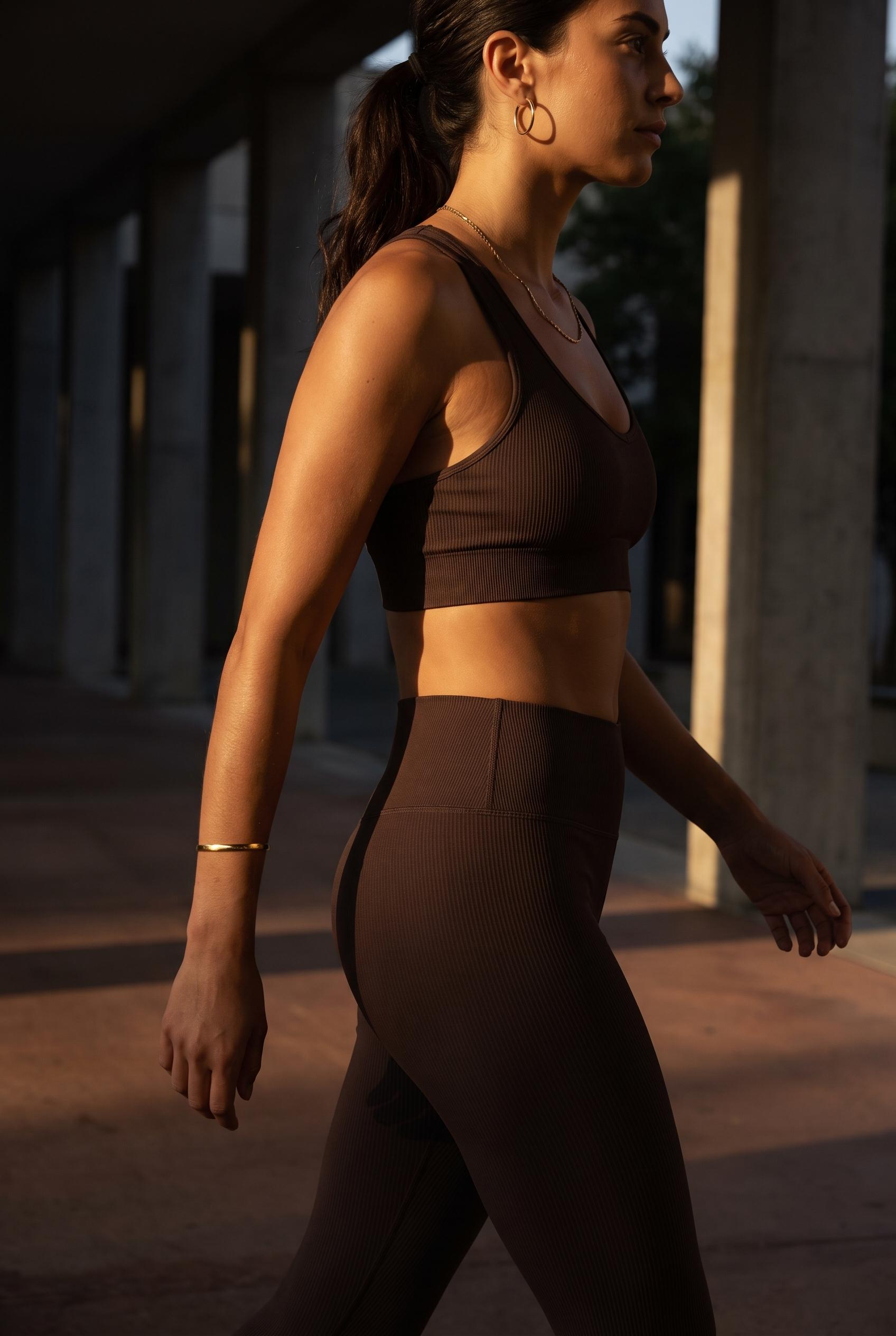 Woman walking in golden light wearing gold hoops, chain and cuff