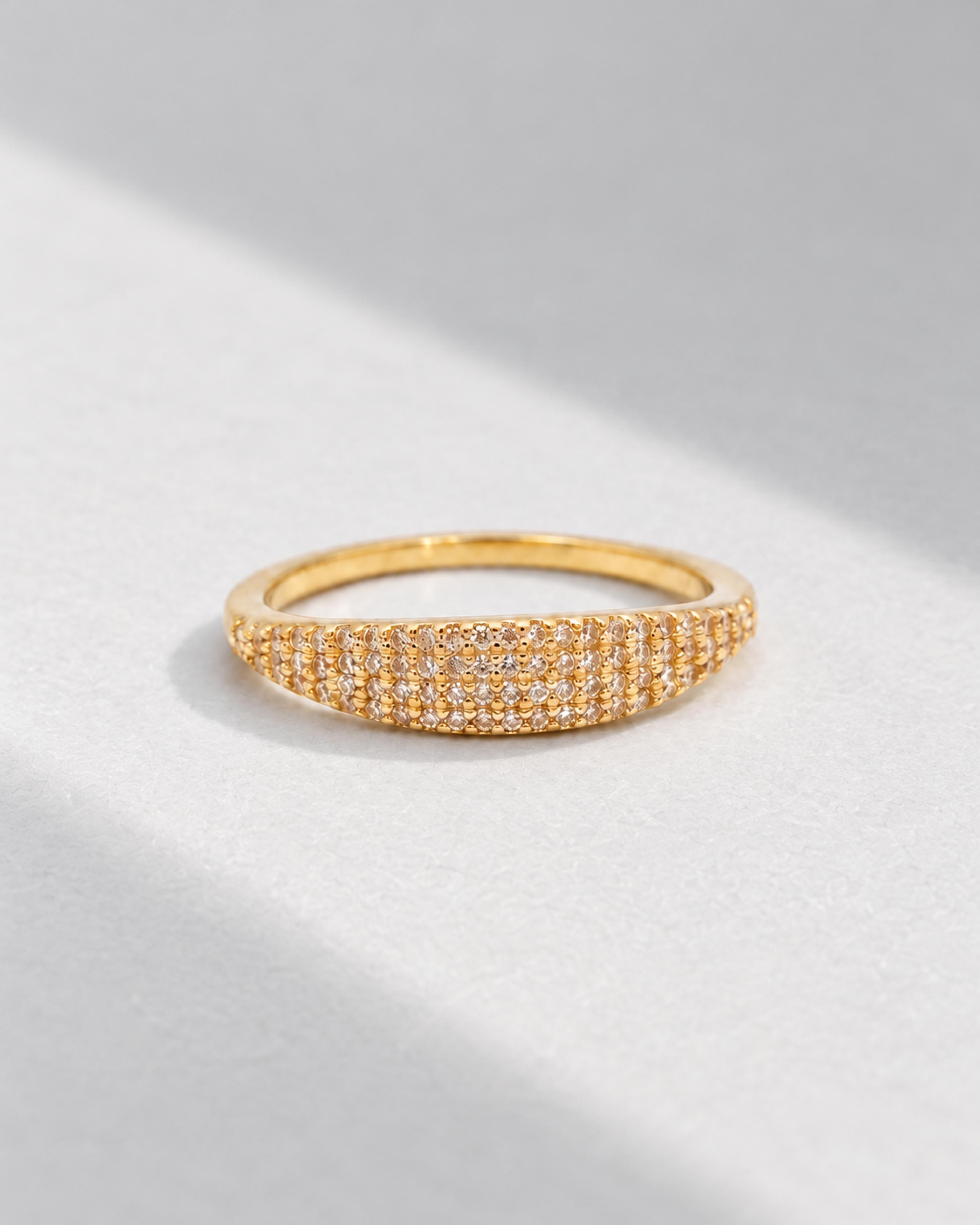 Gold pavé ring on a pale gray background