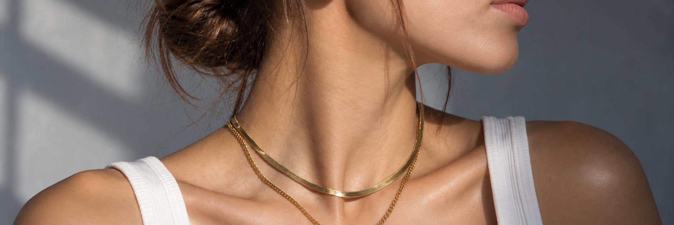 Herringbone and chain necklaces layered on the neck
