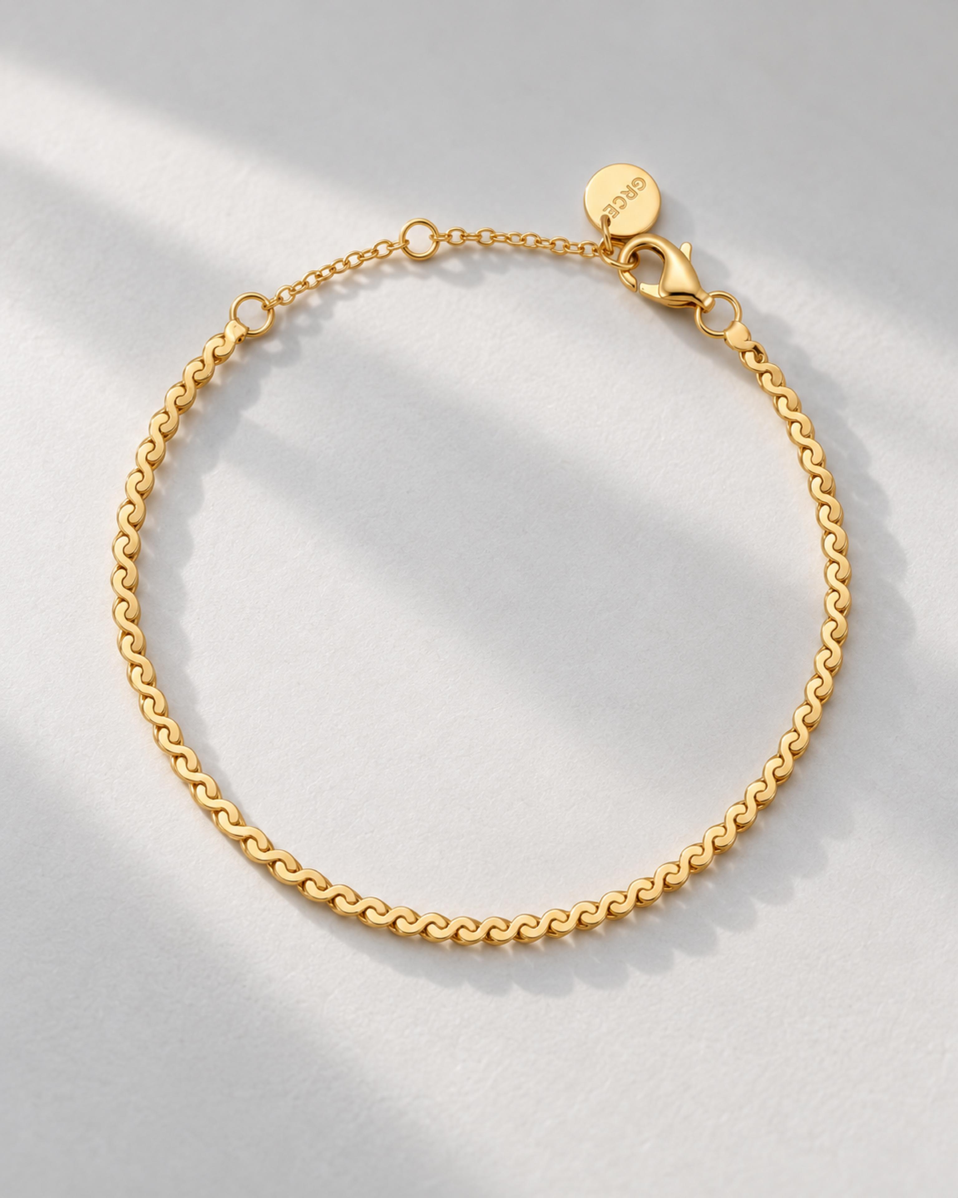 Gold serpentine bracelet on a pale gray background