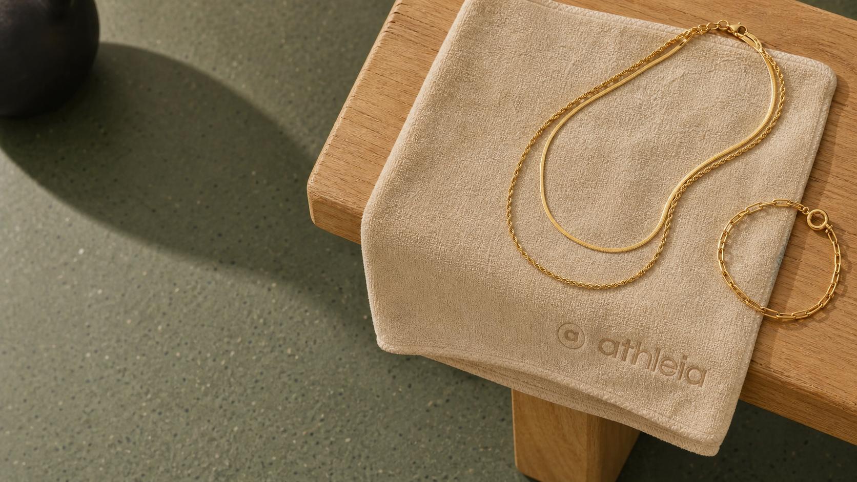 Athleia gold jewelry arranged on a beige Athleia workout towel