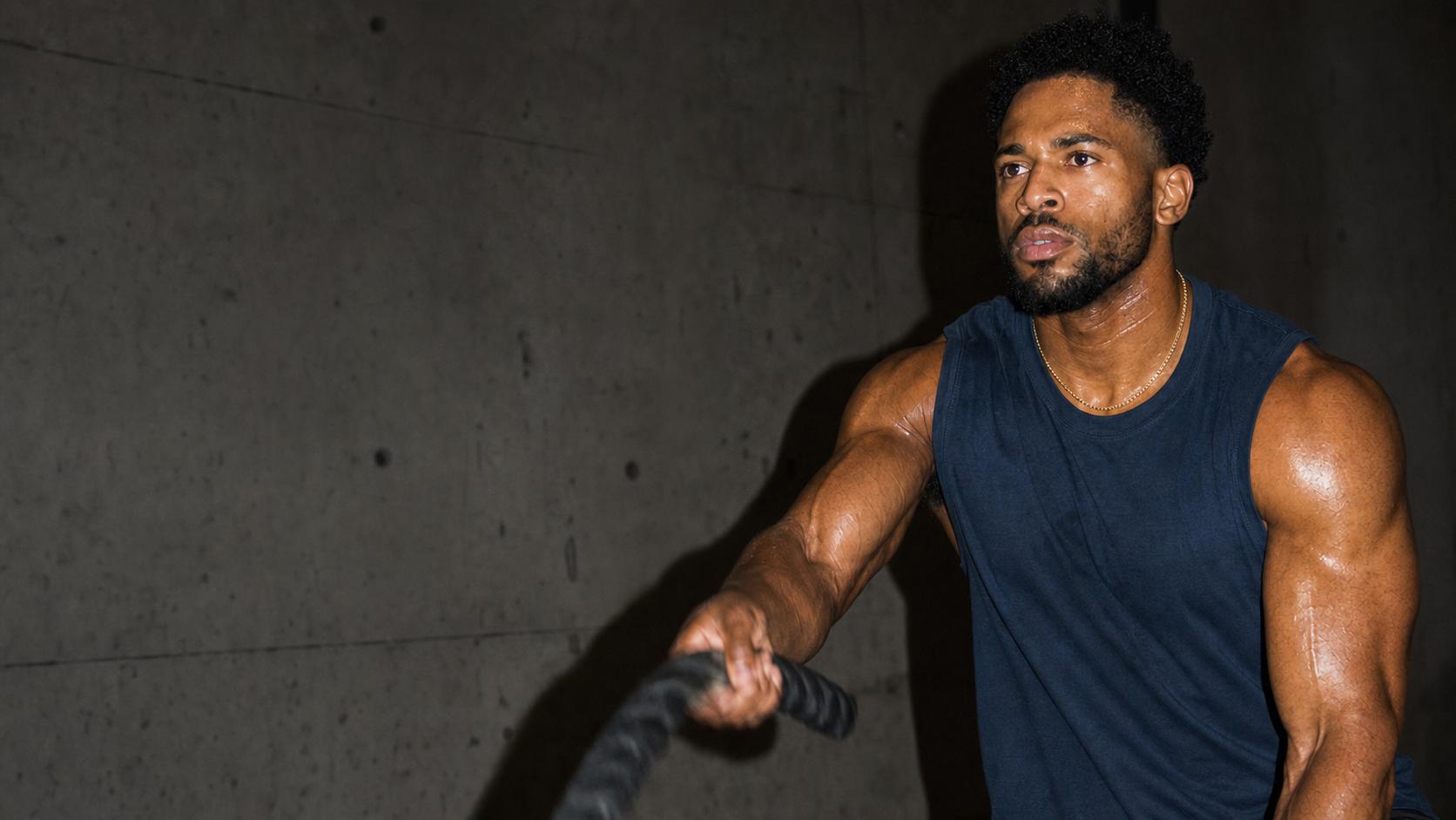 Athlete training with battle ropes while wearing a gold chain.