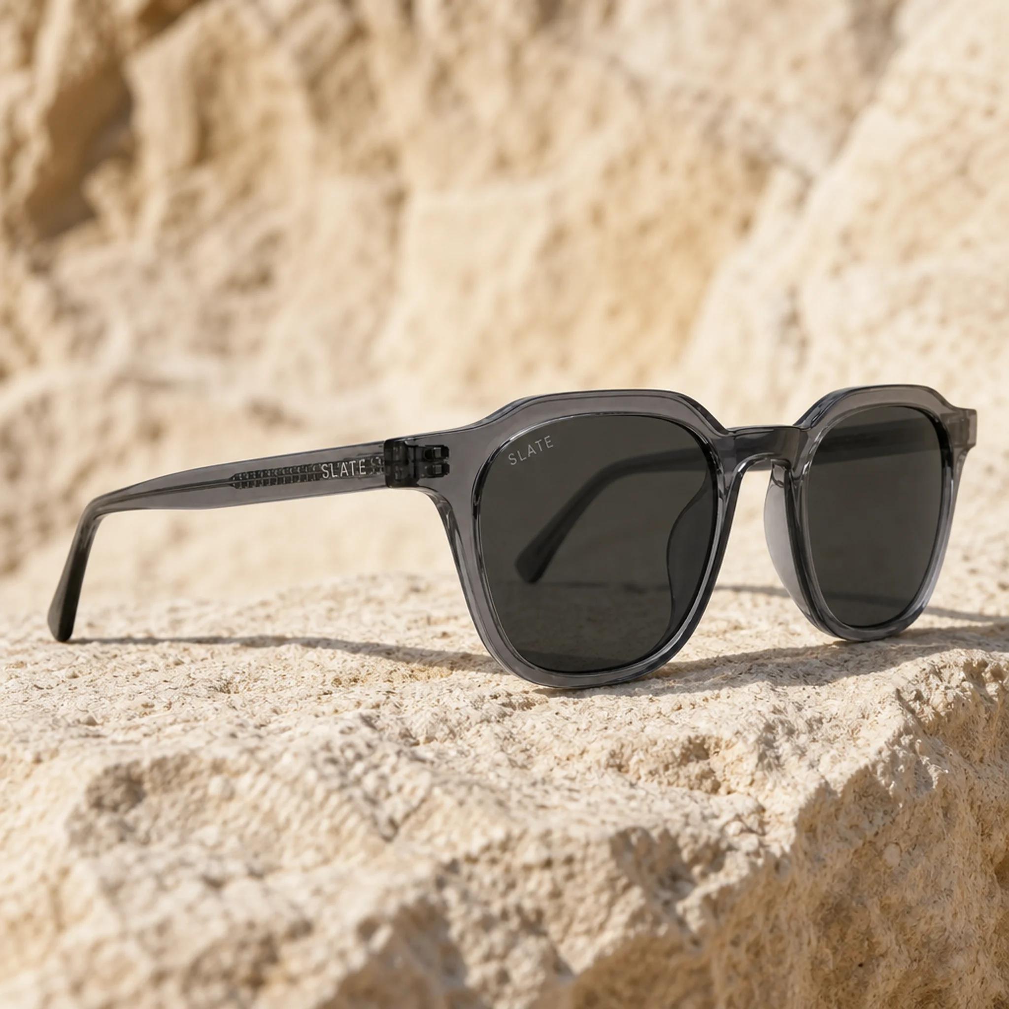 Slate Basin sunglasses in smoke gray translucent acetate on sunlit stone